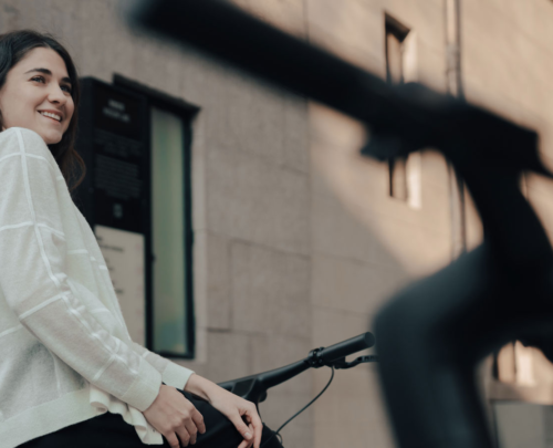 Woman smiles beside Reany e-bike, ready for urban ride.